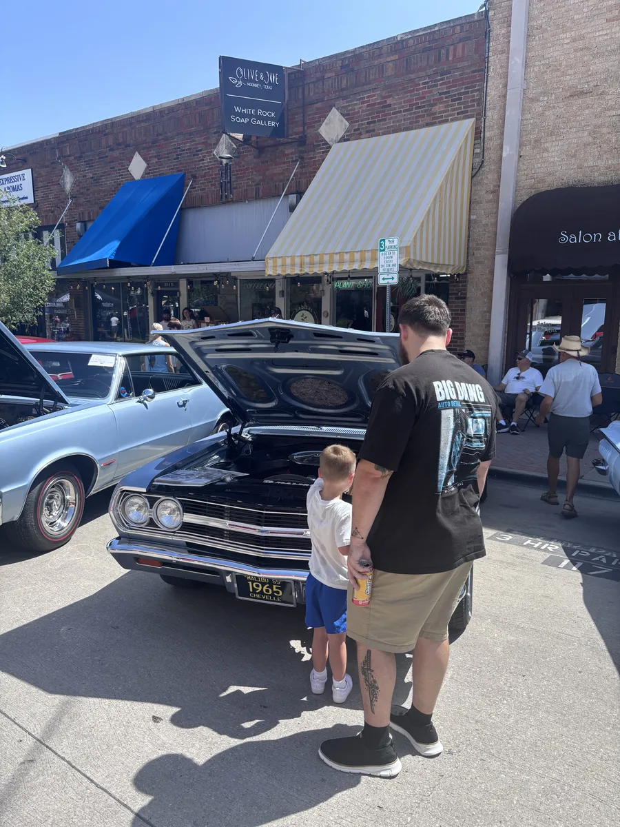 Ethan with his son at a McKinney car show, wearing a Big Dawg Auto Detail shirt